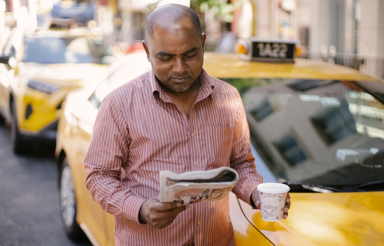 Man with coffee and newspaper near cab